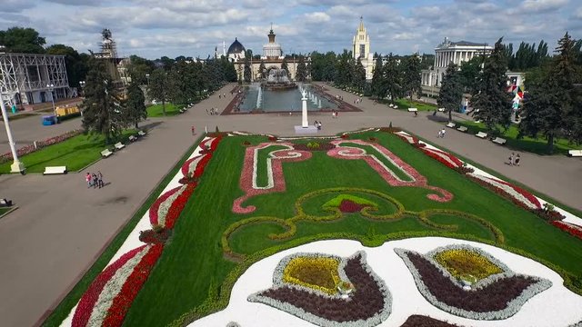 Vdnkh. Moscow. Historical Building Complex. Pond at Square With Fountain. Rows of Fir Trees. Green Park. People Walking. Flowers on Lawn. Summer