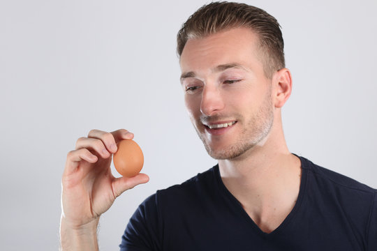Jeune homme regardant un œuf dans sa main  