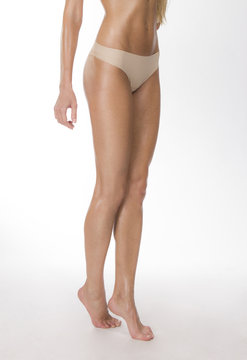 Healthy woman's legs in beige thongs