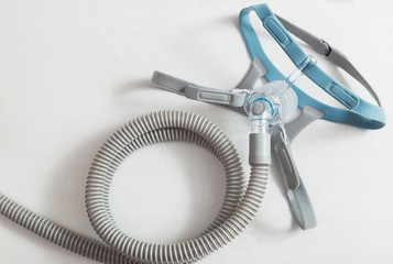 CPAP headgear mask, connecting with strap and hose laying on a bed