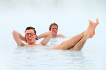 Fototapeta premium Young men relaxing in blue waters from a hot spring with sulfur and silica in Iceland