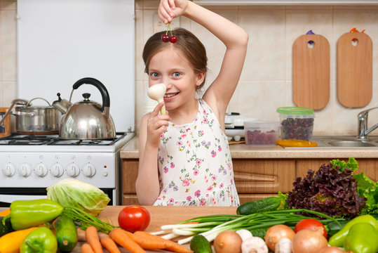 child girl with fruits and vegetables in home kitchen interior, healthy food concept, hold garlic in hands