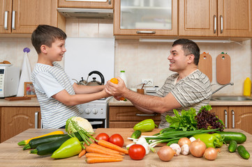 Father and son having fun with vegetables in home kitchen interior. Man and child. Fruits and vegetables. Healthy food concept