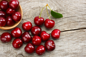 cherries in bowl on old wooden background. Top view with copy space.