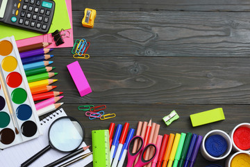 school and office supplies. school background. colored pencils, pen, pains, paper for  school and student education on dark wooden background. top view with copy space