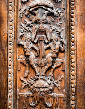 Old wooden gate engraved with demonic figures.