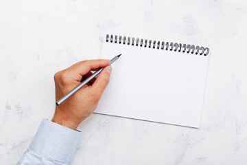 Lefty writes in empty notebook on white table top view. International Lefthanders Day.