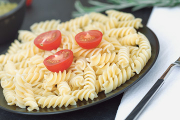 Italian pasta with tomatoes on the black plate