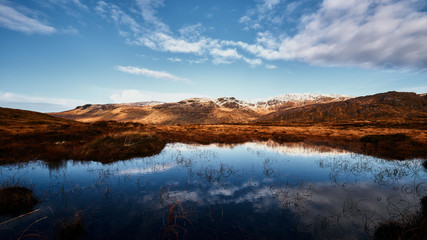 Berge bedeckt mit Schnee im Winter in Donegal Irland mit See im Vordergrund und einem bew&ouml;lkten Himmel
