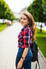 Summer sunny lifestyle fashion portrait of young stylish hipster woman walking on the street with backpack