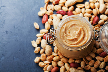 Peanut butter jar and heap of nuts on vintage table with copy space for text. © juliasudnitskaya