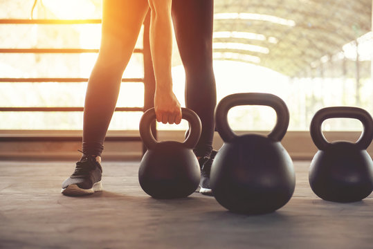 Fitness training with kettlebell in sport gym with sunlight effect.