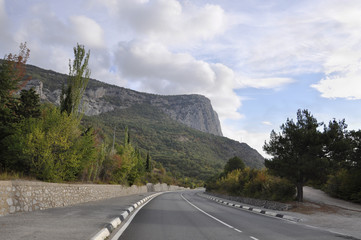 Fototapeta na wymiar Road in the evening in early autumn on the background of high mountains