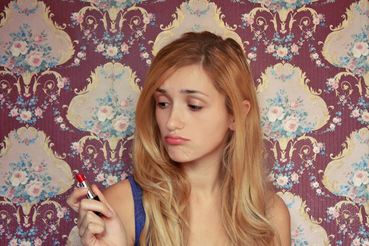 portrait of blonde Girl in green dress applying lipstick