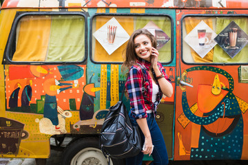 Fototapeta na wymiar Young beautiful girl in stylish clothes in front of old broken bus posing in city street