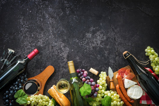 Wine bottles with grapes, cheese, ham and corks