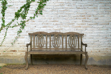 The wall is made of brick  then painted in white and old wooden chairs. There are creepers on the...