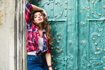 close up portrait of cute smiling woman on a background of green vintage door wearing casual clothes in summer city