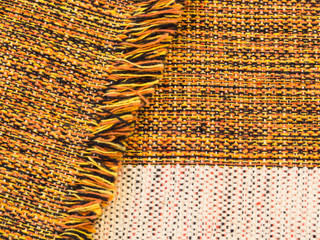 Close-up of handmade ruddy cotton fabric blended of orange, black, yellow and white, folded with...