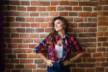 Serious brunette woman against red brick wall closeup
