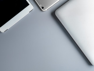Flat lay and minimalist image of laptop, smartphone and tablet on gray background with copy space