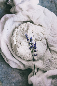 Fresh cooking homemade cottage cheese with lavender flowers in gauze textile over gray metal background. Top view. Rustic style, day light. Toned image