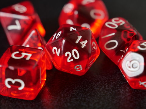 Close up on red transparent gaming dice, highlighting the d20 at the center with a 20 which is a significant number in tabletop gaming
