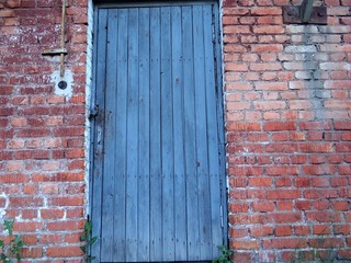 Wooden old painted blue door in the brick wall.