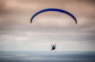Colorful hang glider/paraglider against the blue sky