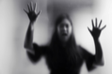 Horror scary shadow of woman behind the matte glass in black and white. Blurry hand and body figure abstraction