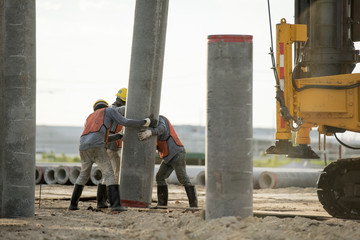 Construction team work in standard construction safety uniform installing precast concrete pile...