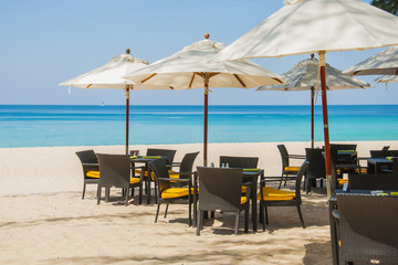 Table , chairs and umbrella on beach restaurant with tropical sea at Phuket island