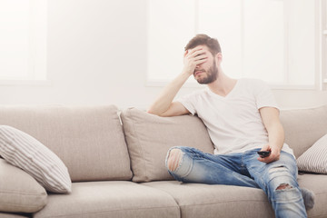 Fototapeta premium Young man watching television, using remote control