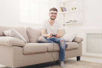Happy young man at home playing video games
