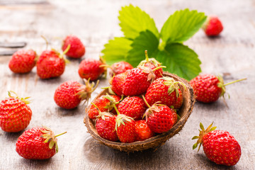 Strawberries in a small bowl and on wooden table