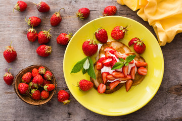 Fritters with yogurt, sliced strawberries and mint leaves on a plate. Top view