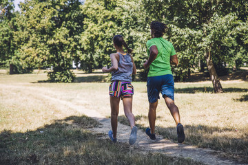 Fototapeta premium Young couple running in the park on a sunny day