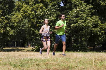 Obraz premium Young couple running in the park on a sunny day
