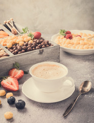 Healthy breakfast with coffee, variety of cold quick breakfast cereals and berries in old gray wooden box, selective focus. Retro style toned.