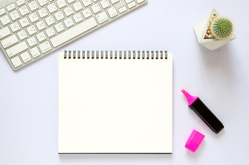 Computer keyboard with blank notebook, cactus, marker color pen on white desk.