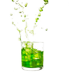 Glass of cold lime green drink with water splash and ice cubes.