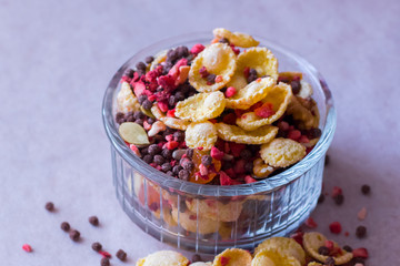 Plate of homemade muesli with cornflakes, freeze dried strawberry, walnuts, chocolate balls, pumpkin seeds