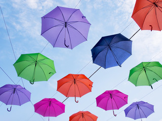 Umbrellas against blue sky.  Visible wires holding them.