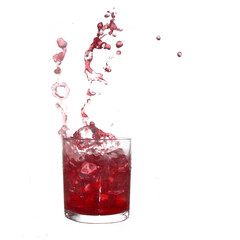 Glass of cold red fruity drink with water splash and ice cubes.