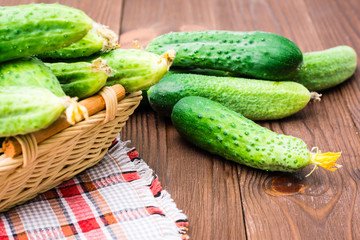 Fresh cucumbers in a basket and on a wooden table