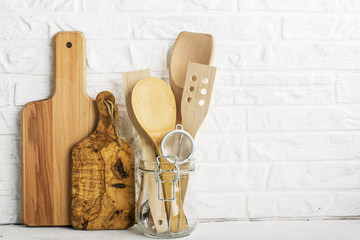 Kitchen tools, olive cutting board on a kitchen shelf against a white brick wall. selective focus