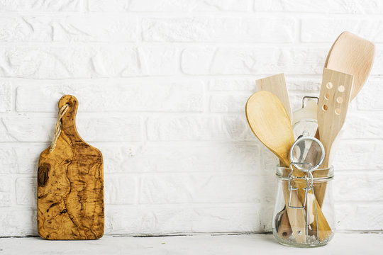 Kitchen tools, olive cutting board on a kitchen shelf against a white brick wall. selective focus