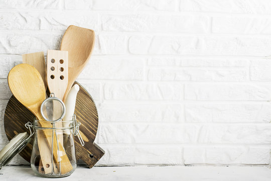 Kitchen tools, olive cutting board on a kitchen shelf against a white brick wall. selective focus