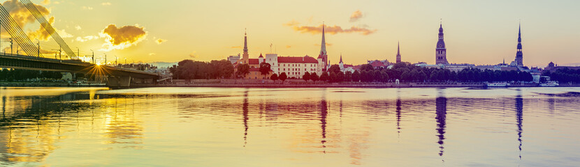 Naklejka premium Panoramic view on old Riga city from left bank of the Daugava river. Riga is the capital of Latvia and famous Baltic city widely known among tourists due to its unique medieval and Gothic architecture