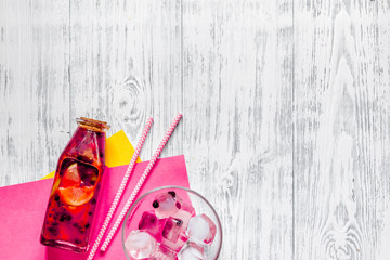 Bottle of fresh lemonade, fruits and ice cubes on wooden background top view copyspace